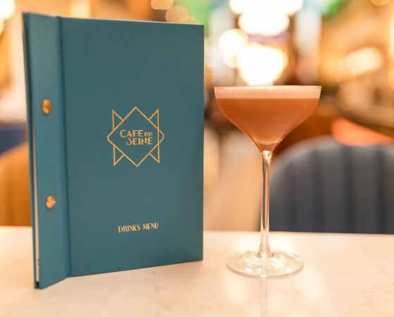 A cocktail beside a cocktail menu